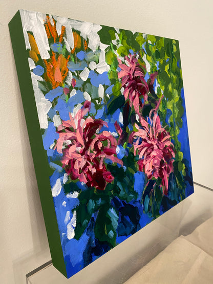 Side view of painting with pink flowers and green leaves against a blue background