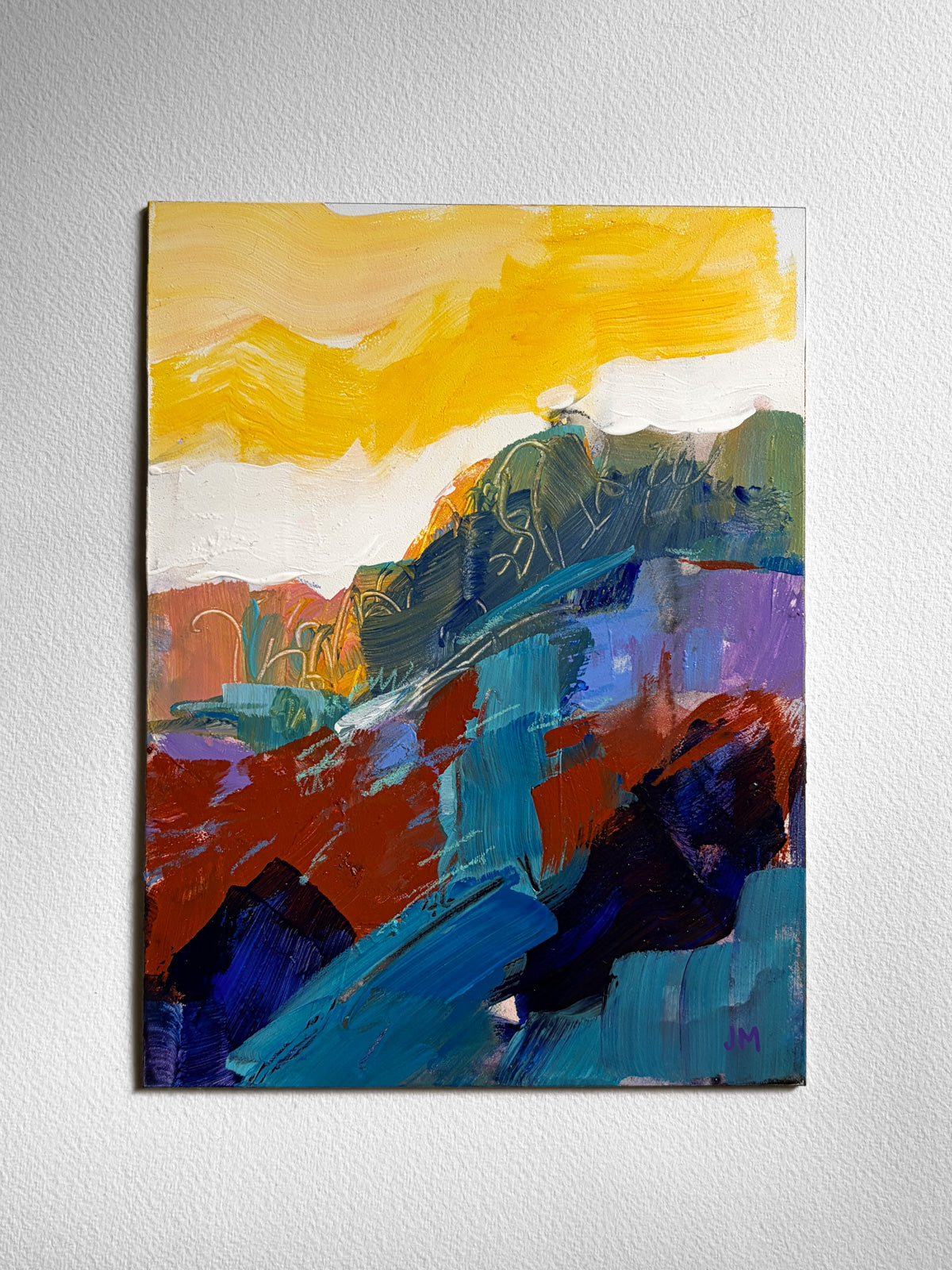 An abstract landscape painting on board, featuring bold brushstrokes of yellow, blue, red, green, purple, and black, displayed on a textured off-white wall.