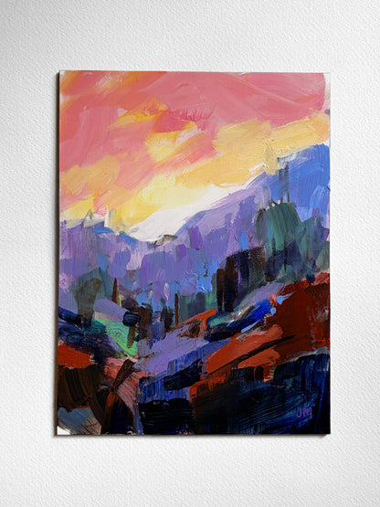 An abstract landscape painting on board, featuring a vibrant sunset sky in pink, yellow, and orange above purple mountains and dark blue foreground elements, displayed on a textured white wall.
