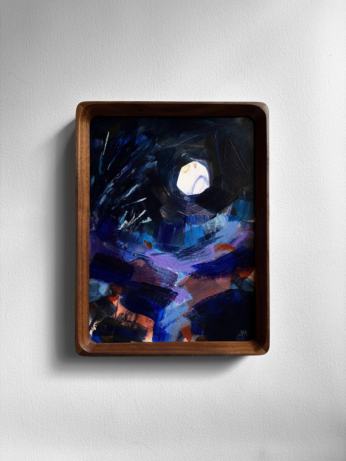 An abstract painting of a night sky with a bright moon, enclosed in a dark brown wooden frame and mounted on a light gray wall.