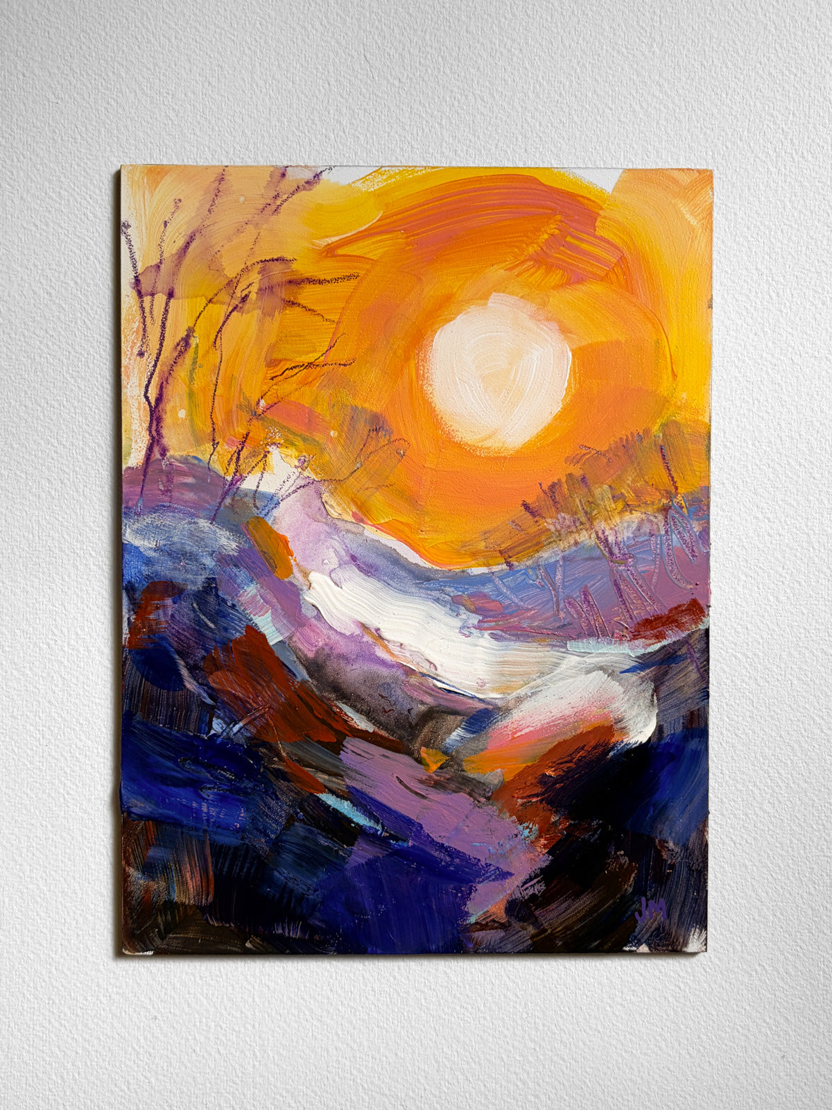 An abstract landscape painting on board, featuring a bright yellow and orange sun over purple, blue, and white mountainous terrain, displayed on a textured white wall.