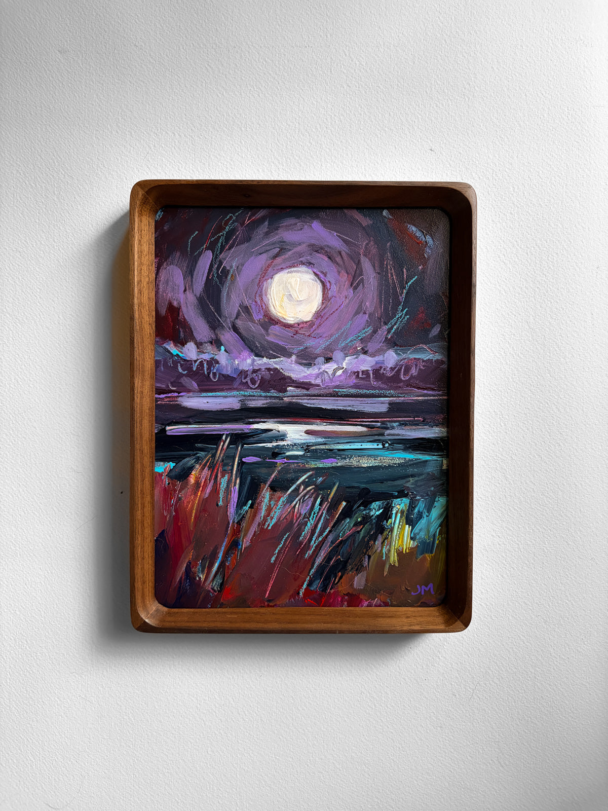 A framed painting of a moonlit landscape with swirling violet sky, dark water, and red-and-teal grasses, displayed on a light gray wall.