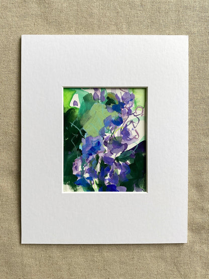 Purple and green matted floral artwork on a textured beige surface
