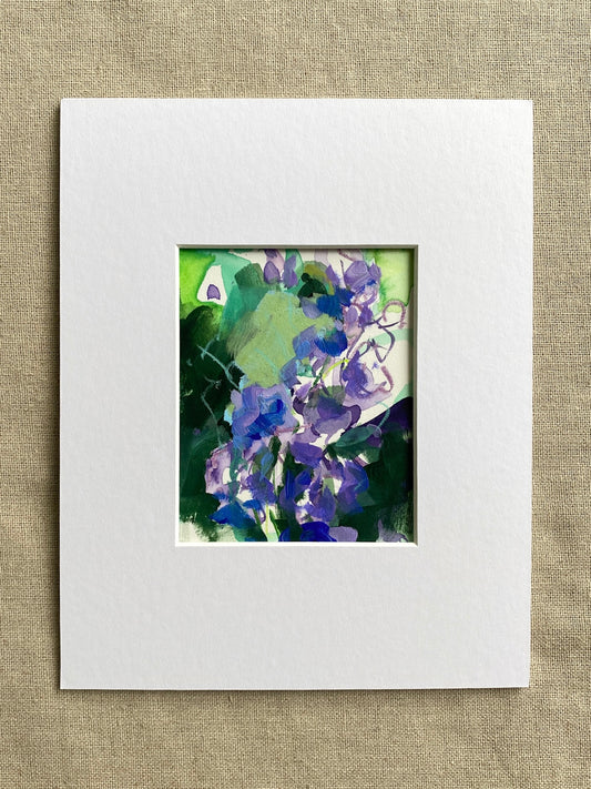 Purple and green matted floral artwork on a textured beige surface