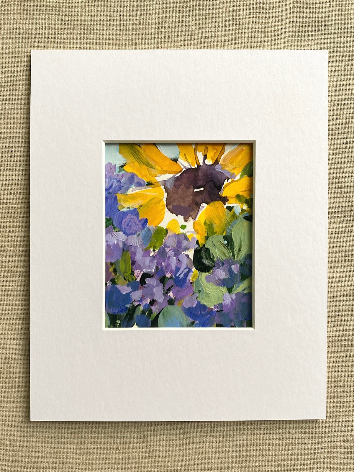 Matted artwork of yellow sunflowers and purple flowers on a textured beige background
