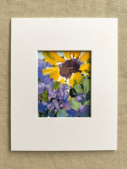 Matted artwork of yellow sunflowers and purple flowers on a textured beige background
