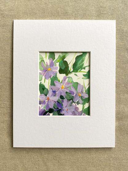Matted artwork of purple flowers and green leaves on a textured beige background
