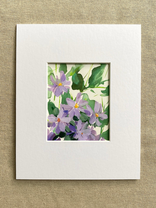 Matted artwork of purple flowers and green leaves on a textured beige background