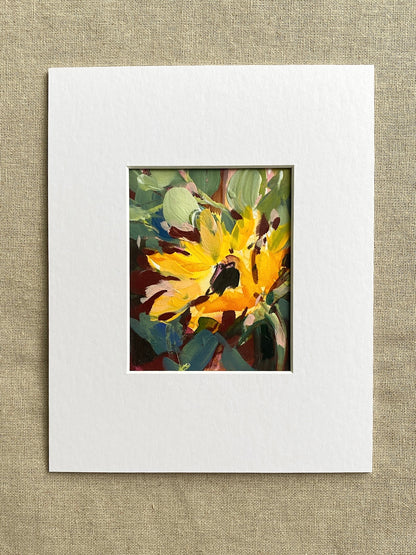 Matted artwork of a sunflower and green leaves on a textured beige background