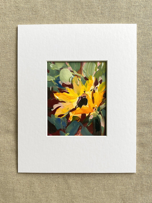 Matted artwork of a sunflower and green leaves on a textured beige background