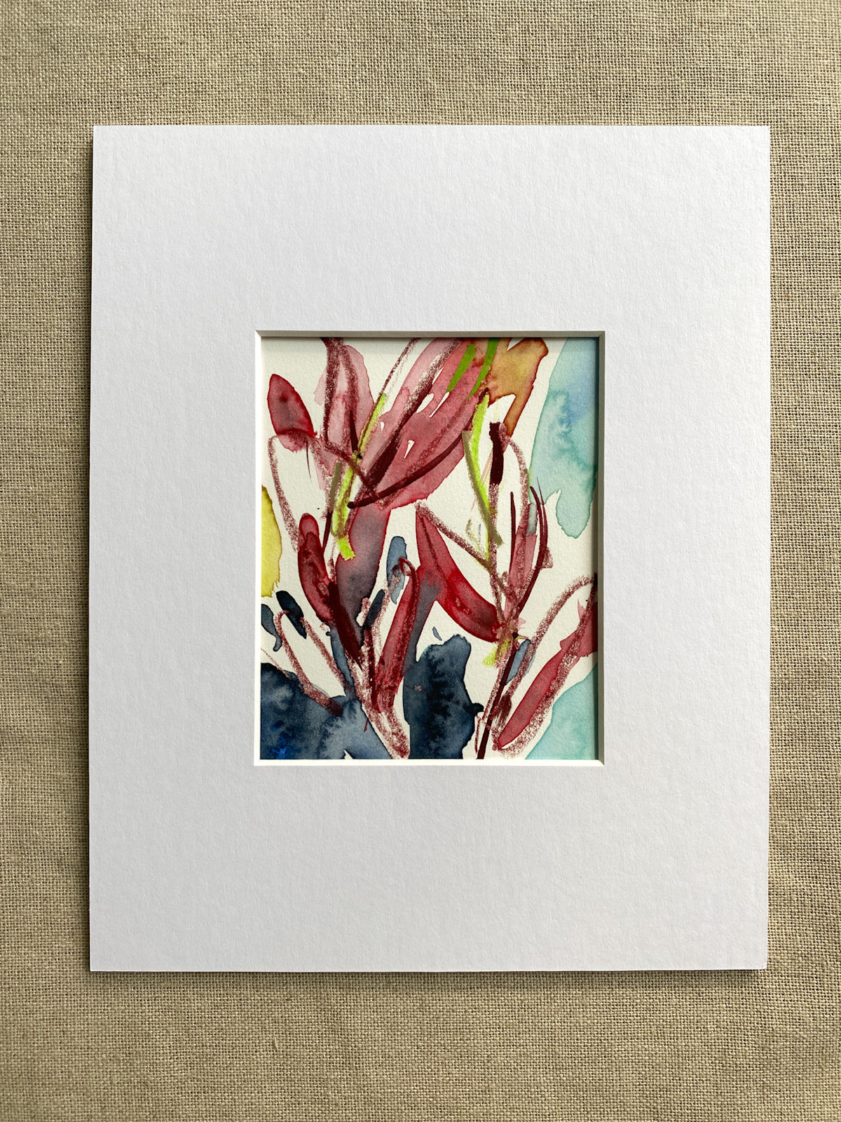 Matted original artwork with a colorful abstract design of red leaves on a textured beige background