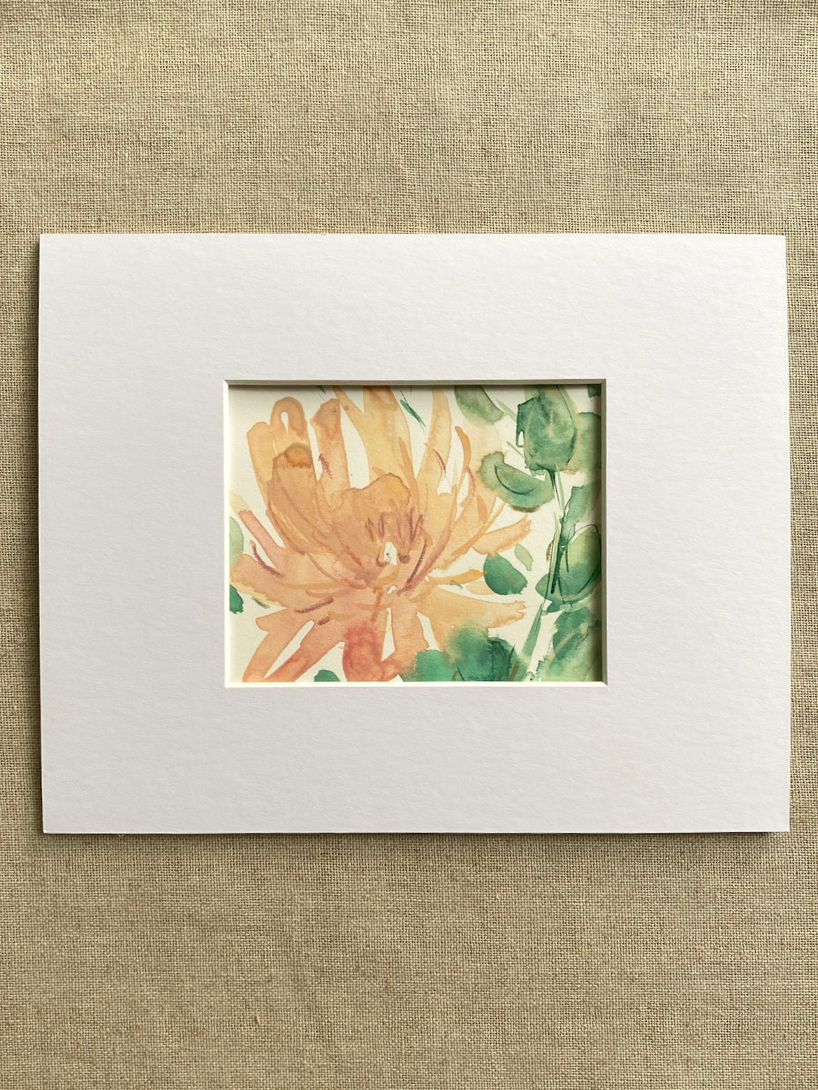 Matted artwork of a peach and green floral design on a textured beige background