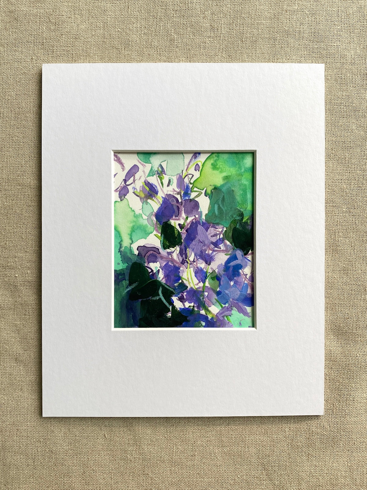 Floral abstract artwork with purple and green colors in white mat on beige textured background